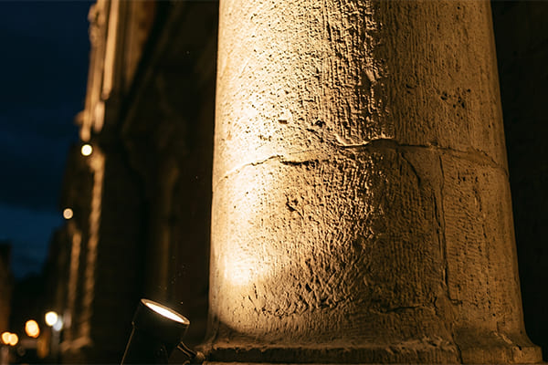 A close-up shot of a narrow beam spotlight grazing up a textured stone column.
